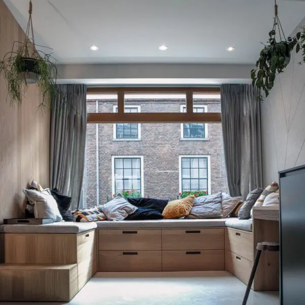 Woonkamer met ingebouwde houten zithoek en grote ramen – centrum Utrecht