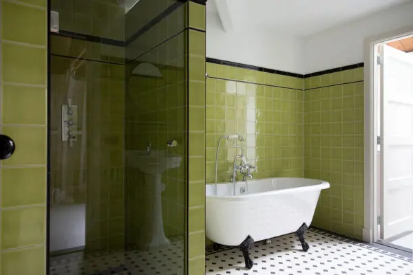 Groene badkamer met vrijstaand bad en mozaïektegelvloer.