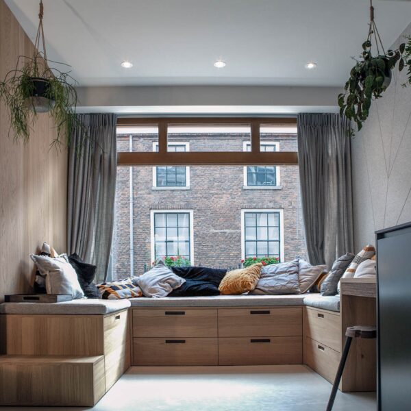 Woonkamer met ingebouwde houten zithoek en grote ramen – centrum Utrecht