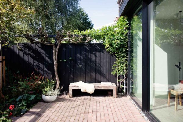Achtertuin met hout bankje grenzend aan uitbouw – jaren ’30 woning Tuinwijk Oost Utrecht