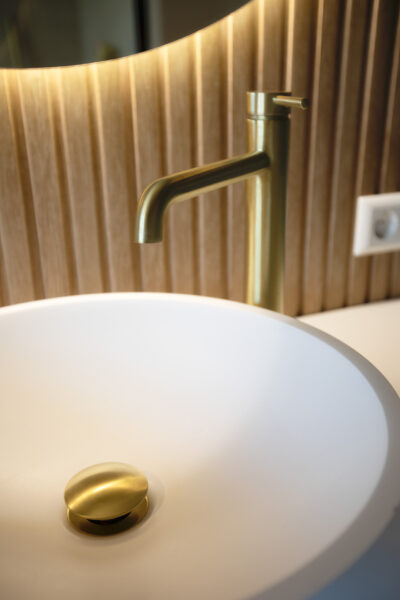 Wastafel met messing kraan en houten achterwand – villa Het Gooi