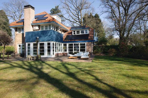 Achterzijde villa met uitbouw en openslaande deuren naar tuin – Het Gooi