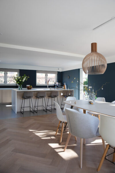 Eethoek met witte stoelen en houten lampen – villa Het Gooi