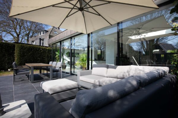 erras met loungeset en parasol naast glazen uitbouw – jaren ’30 woning Wilhelminapark Zeist